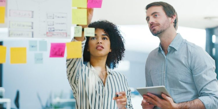 Shot of a young businessman and businesswoman using a digital tablet while having a brainstorming session in a modern office