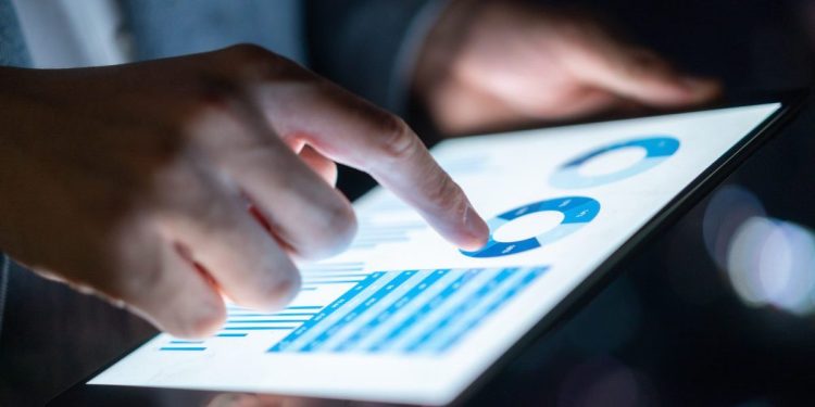 Businessperson gathering business intelligence data on a digital tablet.