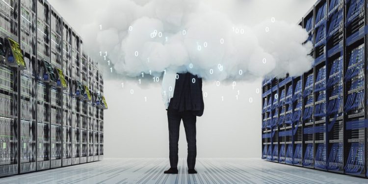 Businessman standing in server room covered by the digital image of a cloud.