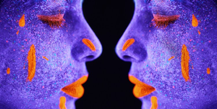 A reflected person with with neon paint on her face