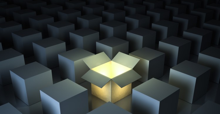 One luminous opened light box glowing among closed white square boxes on dark background with reflections and shadows.