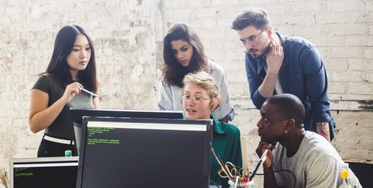 image of various software developers consulting a tablet