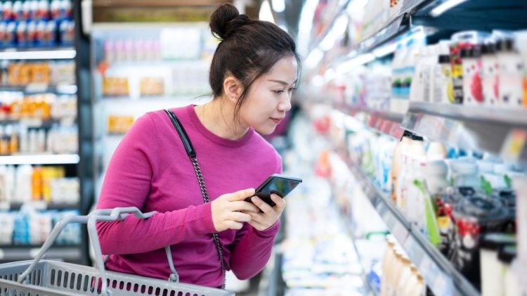 Woman using a smart phone with AI tech while shopping in a grocery store