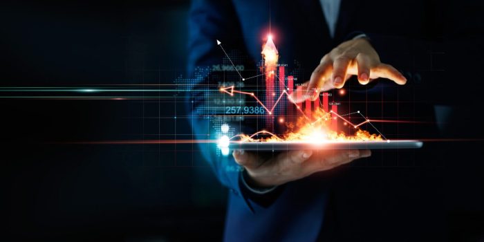 Business person holding tablet and a hot of fire glowing upright arrow with analyzing data and economic growth graph. Strategy. Stock market. Financial and banking. Digital marketing.