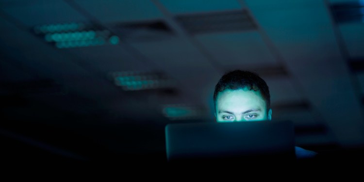 Man looking at computer -- depicting secrecy and privacy.