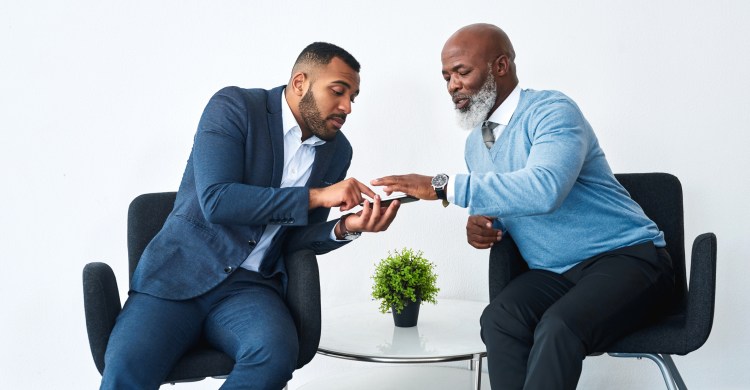Shot of two businessmen using a mobile phone together in  modern office