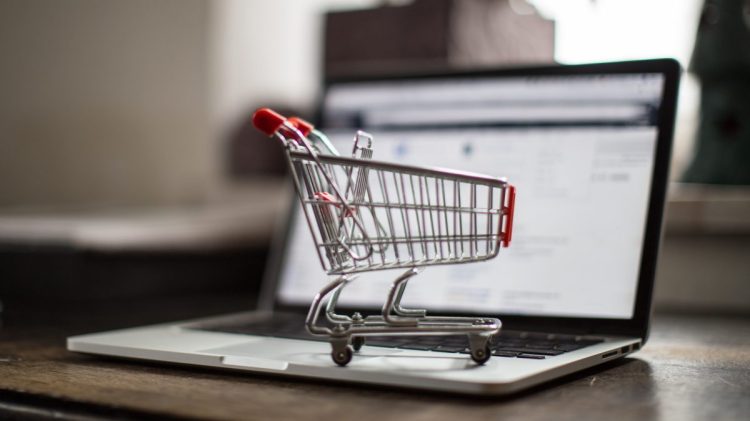 Miniature Shopping Cart on a Notebook with open webpage of a shop