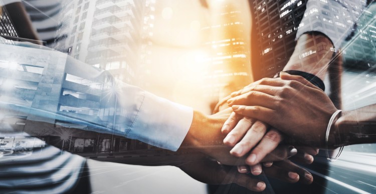 Closeup shot of a group of businesspeople joining their hands together in a huddle. Gender gap and equality concept.