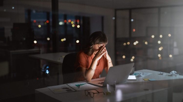 Shot of a young businesswoman looking stressed out while working on a laptop in an office at night.