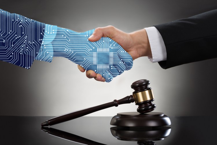 Close-up Of Two Businessman Shaking Hands In Front Of Mallet