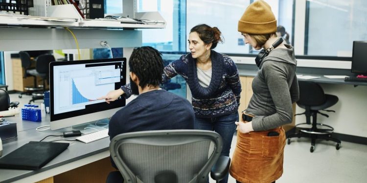 Scientists examining data on computer while working in research lab