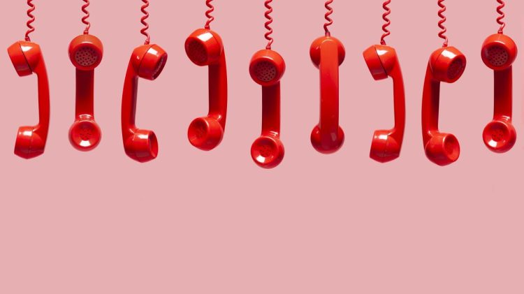 Various views of old red telephone receivers hanging on pink background with texting space, waiting for phone call, customer service concept, vintage telephone receiver