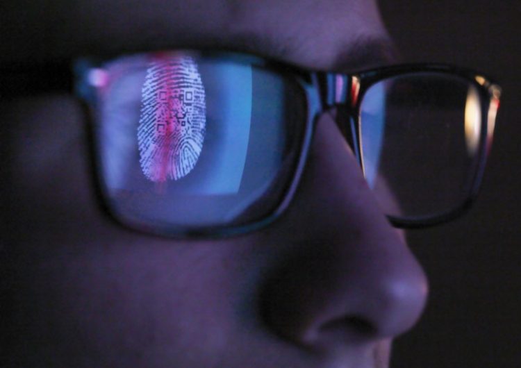 Cybersecurity, reflection in spectacles of access information being scanned on computer screen, close up of face
