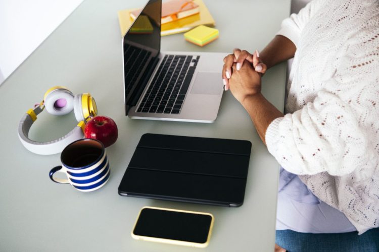 Female freelancer with hands clasped at desk