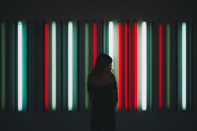 woman standing in front of red, green, and white neon lights, representing holidays, holiday fraud