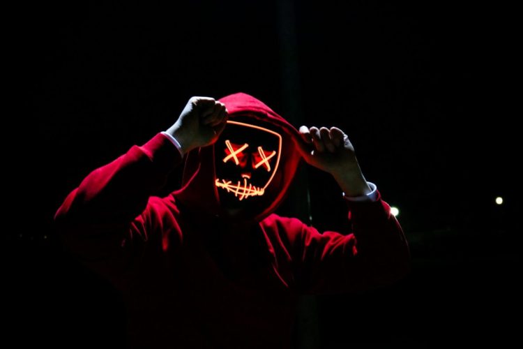 Person in a red hoodie with an LED mask over their face